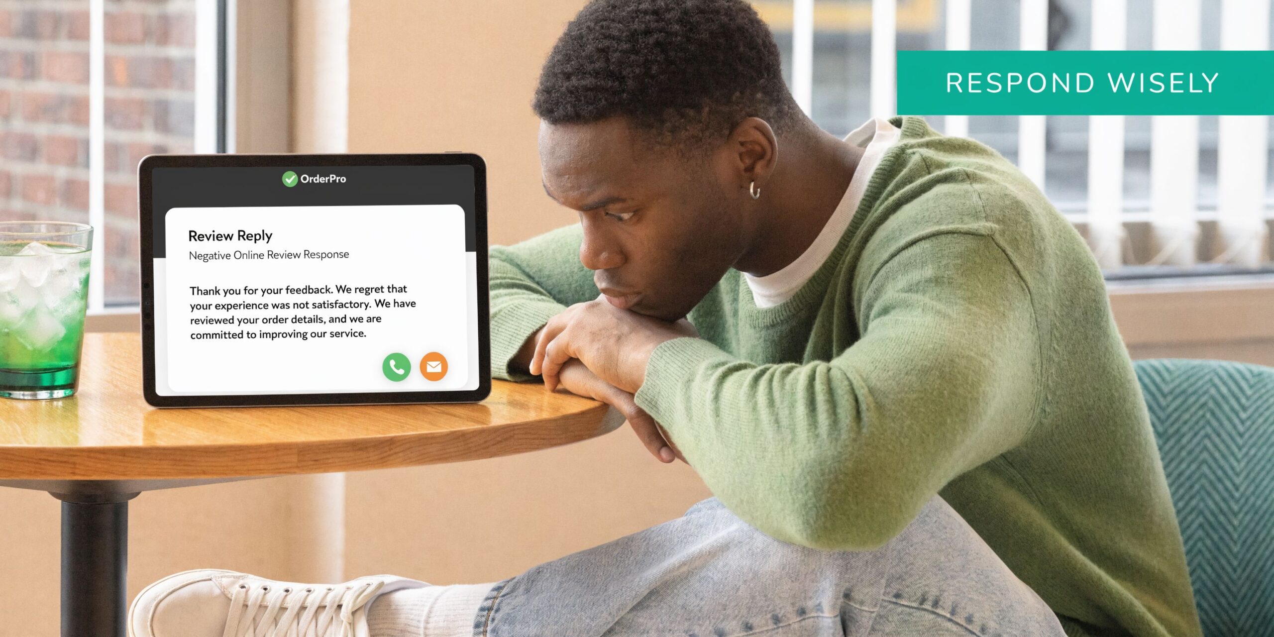 A young man looking thoughtfully at a tablet displaying a professional negative online review response template.